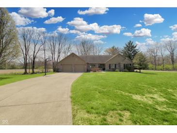 Inviting ranch home featuring a well-manicured lawn, long driveway, and an attached two-car garage at 7608 Andrew Turn, Plainfield, IN 46168