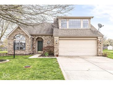 Charming brick home featuring a well-maintained lawn, arched entry, and attached two-car garage at 7715 High View Cir, Indianapolis, IN 46236
