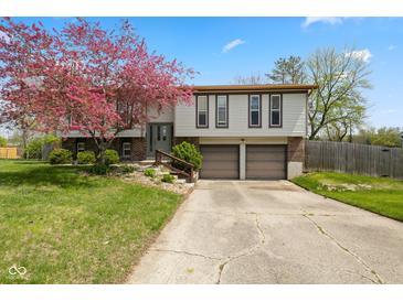 Charming two-story home featuring a well-maintained lawn, mature tree, and an attached two-car garage at 8235 Picadilly Ln, Indianapolis, IN 46256
