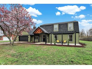 Beautiful home featuring green siding, black trim, lush lawn, mature trees, and a pergola-covered porch at 2103 Postmaster Ln, Greenfield, IN 46140