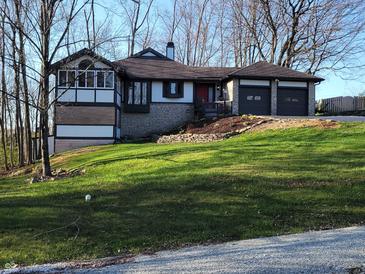 Charming home with a two-car garage, stone accents, and lush green lawn at 5739 E 62Nd Pl, Indianapolis, IN 46220