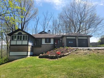 Charming home with a two-car garage, landscaped yard, and a mix of stone and wooden design elements at 5739 E 62Nd Pl, Indianapolis, IN 46220