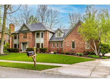 Charming two-story brick home featuring manicured landscaping and a lush green lawn at 12613 Carrington Pl, Carmel, IN 46033