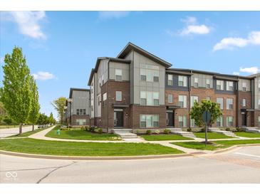Attractive multi-level townhomes with brick and siding, complimented by landscaped lawns and a paved sidewalk at 13349 Minden Dr, Fishers, IN 46037