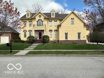 Inviting two-story yellow home featuring well-maintained landscaping and a charming balcony at 1984 Telfair St, Carmel, IN 46032
