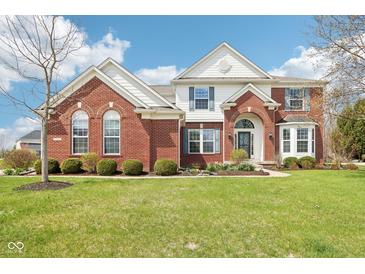 Charming brick home with well-manicured lawn, arched entryway, and classic blue shutters under a beautiful sky at 3932 Long Ridge Blvd, Carmel, IN 46074