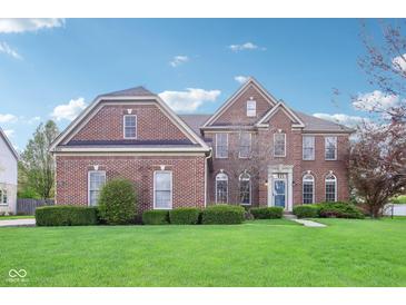 Charming two-story brick home with manicured lawn and lush landscaping under a bright blue sky at 4281 Honeysuckle Ln, Zionsville, IN 46077