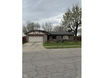 Charming single-story home featuring stone accents, a two-car garage, and a well-maintained front yard at 613 Rahkewood Dr, Indianapolis, IN 46217