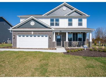 Two-story home featuring a brick facade, attached two car garage, and covered porch with rocking chairs at 7628 Big Bend Blvd, Camby, IN 46113