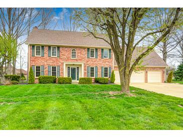 Traditional two-story brick home with an attached two-car garage, green shutters, and manicured landscaping at 7688 Gunsmith Ct, Plainfield, IN 46168