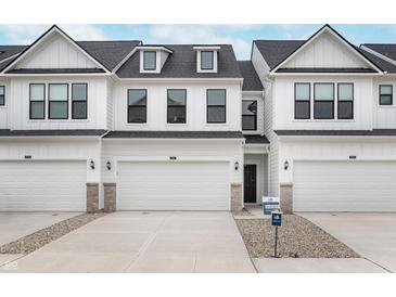 Charming townhome featuring a white exterior, attached garage, and well-maintained landscaping at 10965 Morab Dr, Zionsville, IN 46077