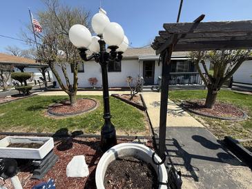 Charming home with decorative landscaping, a black lamppost, and a pergola detail framing the walkway at 1623 S Grant Ave, Indianapolis, IN 46203