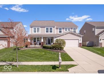 Charming two-story home boasts a manicured lawn, covered porch and attached two-car garage at 19546 Forsythe Dr, Noblesville, IN 46060