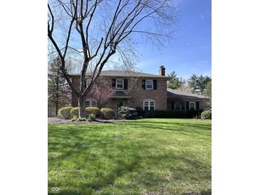 Charming two-story brick home with a manicured lawn and mature landscaping creating great curb appeal at 3911 E 75Th St, Indianapolis, IN 46240