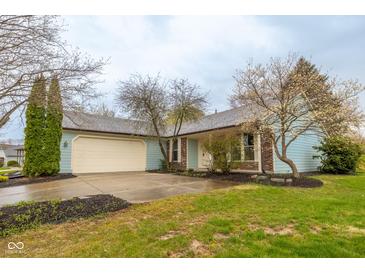 Charming light blue home featuring an attached garage, and an inviting front yard with some trees at 9362 Helmsdale Dr, Indianapolis, IN 46256