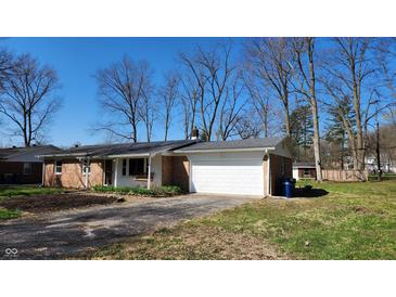 Charming brick ranch home featuring an attached two-car garage and cozy front porch at 9882 Woodbriar Ln, Carmel, IN 46280