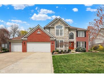 Beautiful two-story home featuring a brick and stone facade, three-car garage, and a well-manicured lawn at 10814 Tallow Wood Ln, Indianapolis, IN 46236