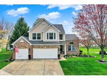 Two-story brick home with three-car garage and a well-manicured lawn at 15890 Concert Way, Noblesville, IN 46060