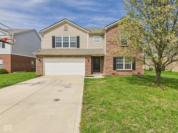 Charming two-story home boasts a brick and tan siding exterior with an attached two-car garage at 11840 Geyser Ct, Fishers, IN 46038