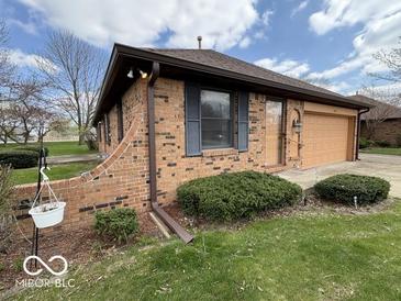 Brick exterior with blue shutters, a lawn, landscaping, and attached garage, offering classic curb appeal at 1215 Willow Springs Blvd, Brownsburg, IN 46112