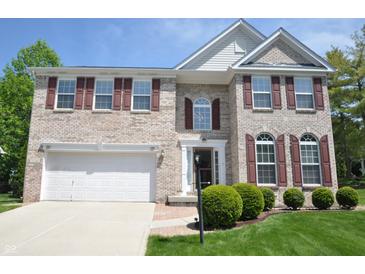 Charming two-story brick home with well-manicured lawn and two-car garage on a sunny day at 12561 Gladecrest Dr, Carmel, IN 46033