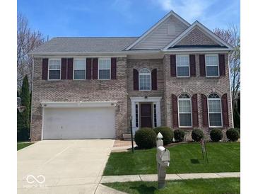 Charming brick two-story home with a two car garage, manicured lawn, and dark shutters at 12561 Gladecrest Dr, Carmel, IN 46033