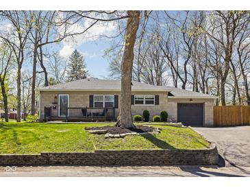 Charming single-story home with stone facade, well-kept landscaping, and attached garage at 1355 E 56Th St, Indianapolis, IN 46220