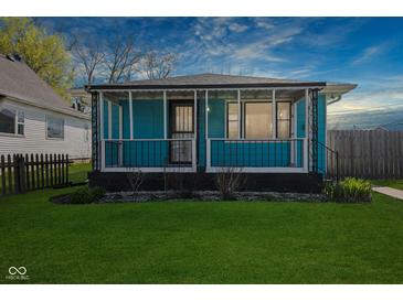 Charming, light-blue, one story home with a covered porch and freshly cut lawn at 1857 Calvin St, Indianapolis, IN 46203