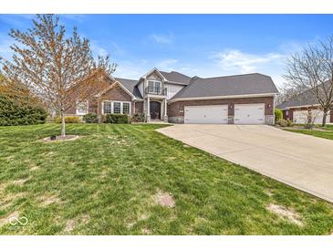 Charming brick home featuring an attached three car garage and a well-manicured front lawn at 621 Foxboro Dr, Avon, IN 46123