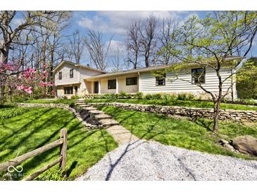 Charming home featuring stone retaining walls, lush lawn, and a winding gravel driveway at 6454 Dean Rd, Indianapolis, IN 46220