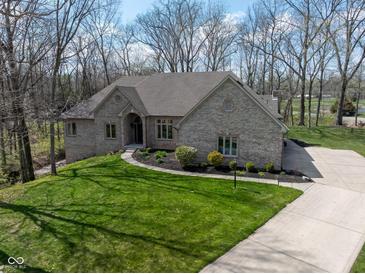 Charming brick home with a well-manicured lawn, lush landscaping, and a concrete driveway at 7424 Campfire Run, Indianapolis, IN 46236