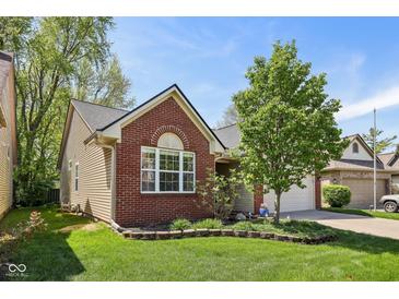 Beautiful home with a well-manicured lawn, landscaped garden, brick accents, and neutral siding at 7450 Deville Ct, Indianapolis, IN 46256