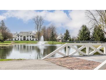 Stunning home featuring a pond, fountain, and a brick pathway with manicured landscaping and architectural charm at 8155 Hunt Club Rd, Zionsville, IN 46077