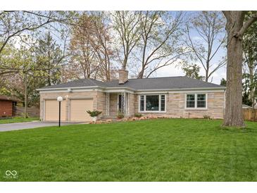 Charming stone home featuring an attached two-car garage and a well-maintained lawn at 928 Forest Blvd N Dr, Indianapolis, IN 46240