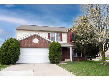 Charming two-story home with red shutters, a white garage, lush greenery, and a beautiful blossoming tree at 12516 Schoolhouse Rd, Fishers, IN 46037