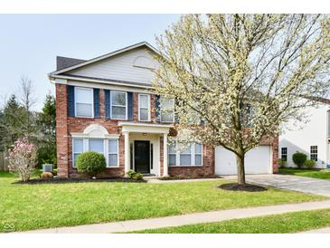 Charming two-story brick home featuring a well-manicured lawn and mature flowering tree at 13858 Meadow Lake Dr, Fishers, IN 46038