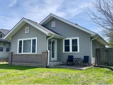Charming single-story home with gray siding, white trim, a brick accent, and a small front patio with seating at 1749 E 52Nd St, Indianapolis, IN 46205
