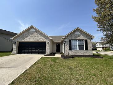 Charming single-story home with a brick facade, black garage door, and well-manicured lawn at 2344 Orchard Creek Dr, Columbus, IN 47201
