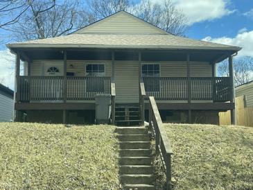Charming home featuring a covered front porch and a classic design, set against a backdrop of trees and a blue sky at 507 W 29Th St, Indianapolis, IN 46208