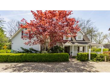 Charming two-story home with gray siding, red maple tree, brick driveway, and manicured front hedge at 7124 Purdy St, Indianapolis, IN 46268