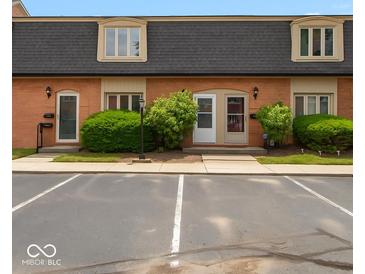 Two-story townhouse with brick exterior, neutral trim, black roof, and parking at 1131 Canterbury S Sq, Indianapolis, IN 46260