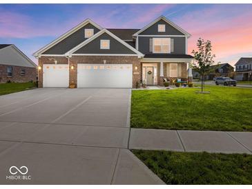 Charming two-story home with a brick and gray facade, three-car garage, and well-manicured lawn at 1305 Bontrager Ln, Shelbyville, IN 46176