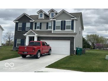 Charming two-story home showcasing a brick and gray siding, a two car garage, and well-manicured lawn at 1573 Vera Blvd, Danville, IN 46122
