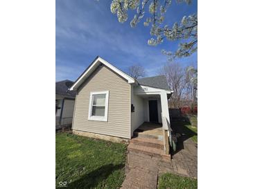 Charming single story home featuring light beige siding and a quaint brick walkway leading to the front entrance at 1710 Thaddeus St, Indianapolis, IN 46203