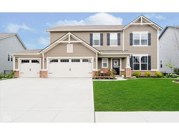 Charming two-story home featuring a well-manicured lawn, a three-car garage, and a welcoming front porch at 17301 Tribute Row, Noblesville, IN 46060
