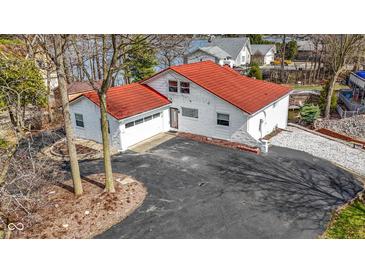 Aerial view of a white home with a red roof, an attached garage, and a spacious paved driveway at 2469 Cape Henry Ct, Cicero, IN 46034