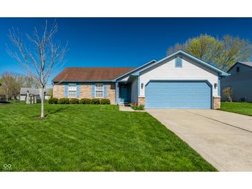 Charming single-story home featuring a well-manicured lawn, a blue garage door, and a brick facade at 7230 Carrie Dr, Indianapolis, IN 46237