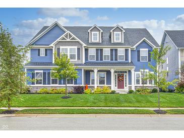 Charming two-story blue home with well-manicured lawn, tasteful landscaping, and welcoming front porch at 12959 Girvan Way, Fishers, IN 46037