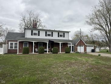 Charming two-story home with brick and white siding, a covered front porch, and well-maintained landscaping at 216 Golf Club Rd, Anderson, IN 46011