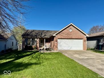 Charming brick home featuring a well-maintained lawn, attached garage, and inviting front porch at 305 S Schroeder Rd, Muncie, IN 47304